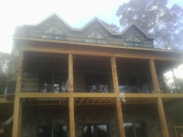Dormers and porch framing on a large log home under construction — Roof Coating work by our crew in Danbury
